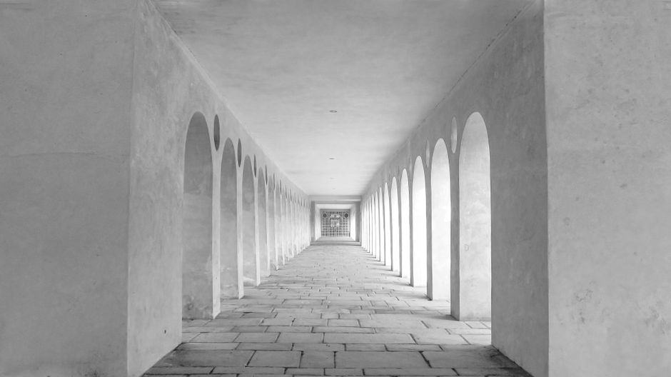 A bright, minimalist white architectural corridor leading towards a light at the end, symbolizing a clear path forward.