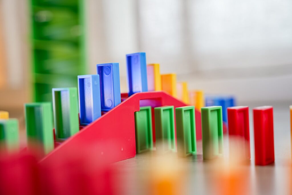Close-up shot of a complex, winding pattern of dominoes on a bright, clean surface, representing a systematic and strategi...