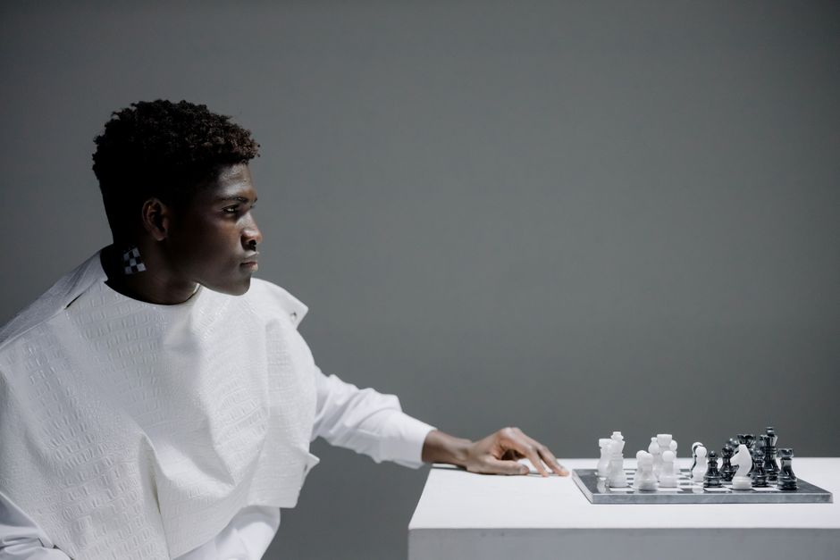 A close-up shot of a person strategically moving a chess piece on a modern chess board, illustrating the need to adapt marketing strategy for 2025.