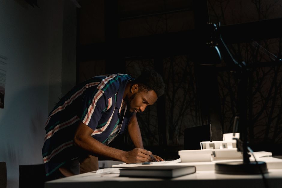 A professional's hand using a stylus to sketch a complex diagram on a futuristic transparent screen in a modern setting.