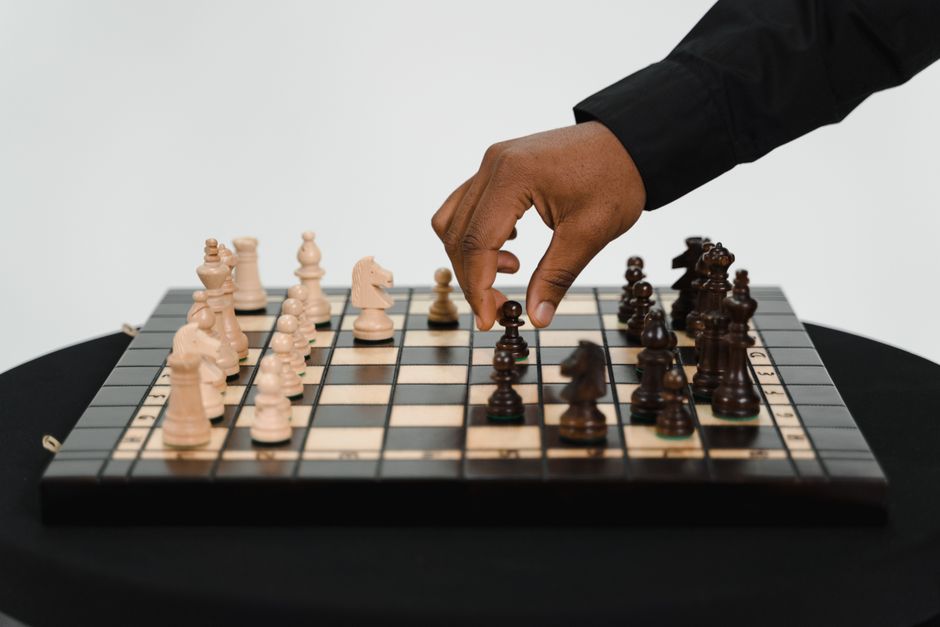 Hand making a strategic move with a chess piece on a minimalist board, symbolizing a decisive pivot in business strategy f...