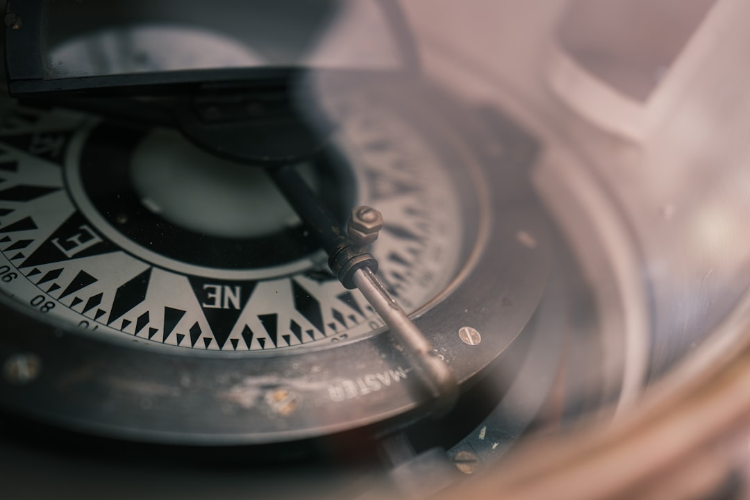 A sleek, modern compass pointing forward, set against a dark, abstract background, symbolizing the need for new direction and measurement in SEO.
