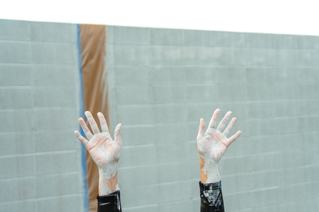 A close-up of hands carefully building a stable, protective structure with modern wooden blocks against a clean background, illustrating a defensive GEO strategy.