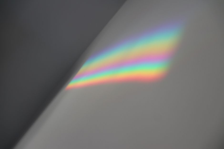 A single beam of light enters a modern glass prism and fans out into a vibrant spectrum of colors, illustrating the concept of 'instant fanout'.